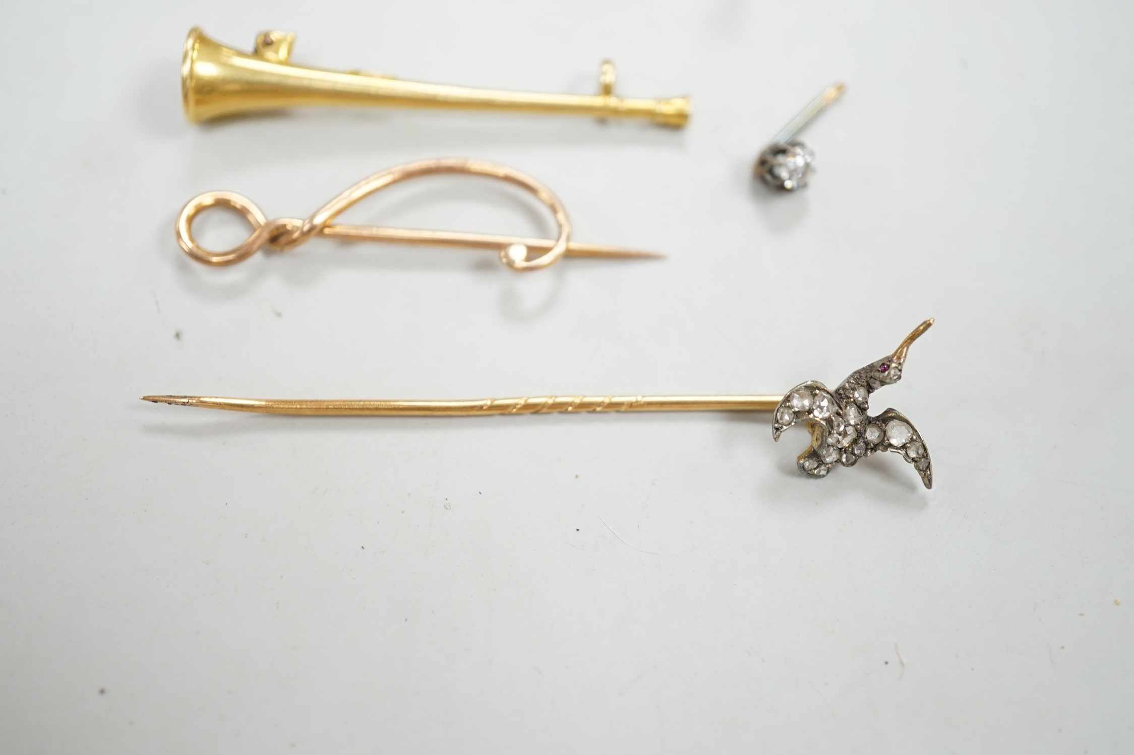 An Edwardian 15ct riding crop brooch(a.f.), 59mm, 2.8 grams, an 18ct hunting horn brooch (lacking pin) 2.1 grams, two Victorian diamond cluster set stick pins including swan in flight, a diamond set pin terminal, gross 4